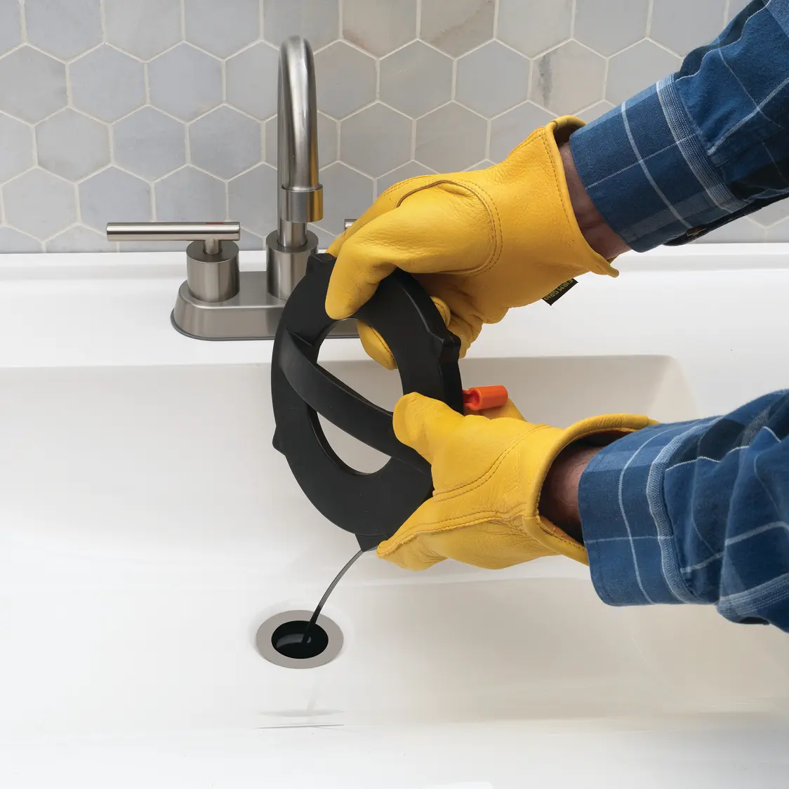Man in gloves using drain cleaner on sink